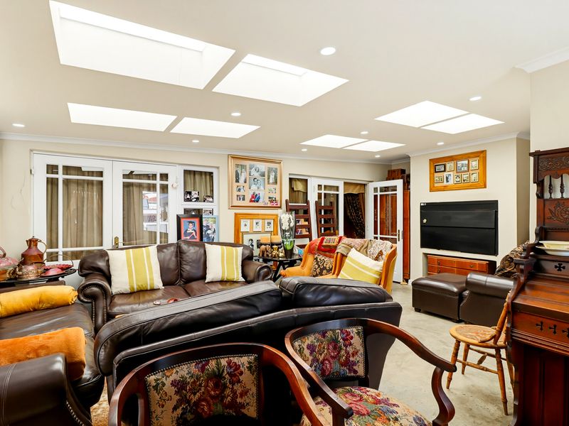 Spacious living room featuring multiple skylights, recessed lighting, and multiple sets of french doors providing ample natural light.