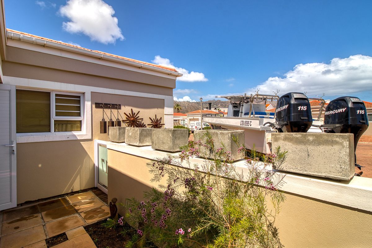 A paved rear patio area featuring a low boundary wall with integrated concrete planters and access to the main dwelling.