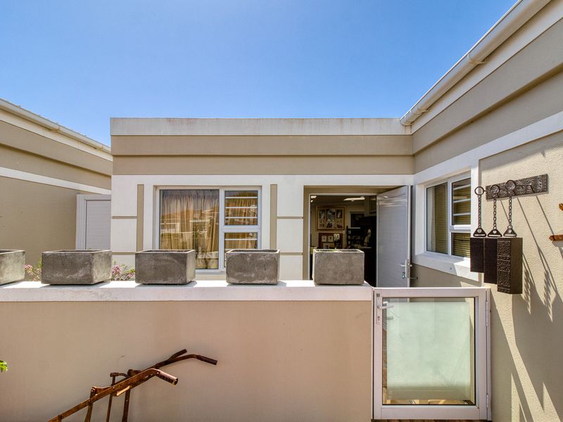 A private courtyard or patio area featuring a low parapet wall, security gate, and access to the interior living space.