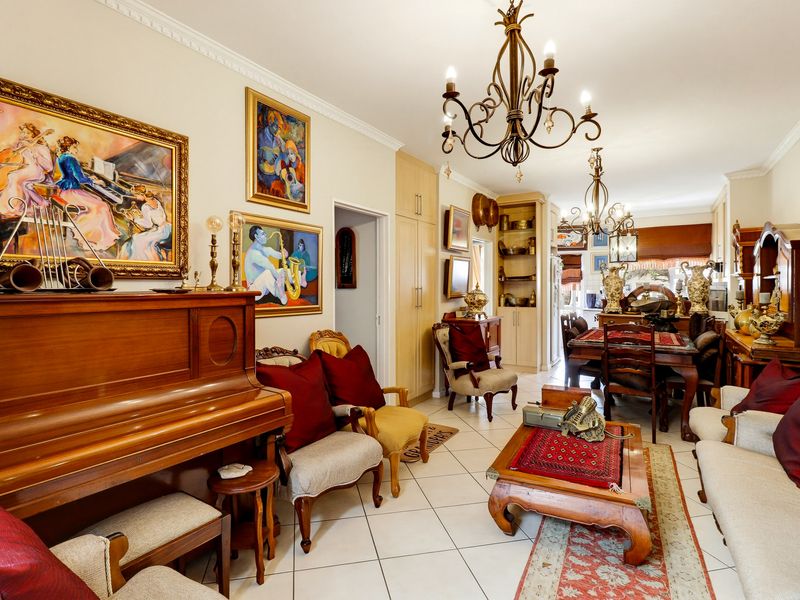 Spacious open-plan living and dining area featuring tiled flooring, decorative crown molding, and elegant wrought iron chandeliers throughout the connected space.