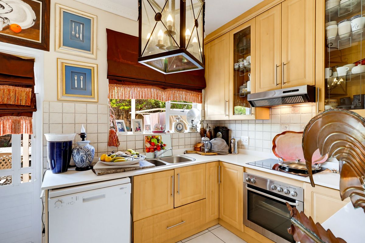 A functional kitchen featuring light wood cabinetry, tiled backsplash, integrated oven and hob, and a double bowl sink with ample storage space.