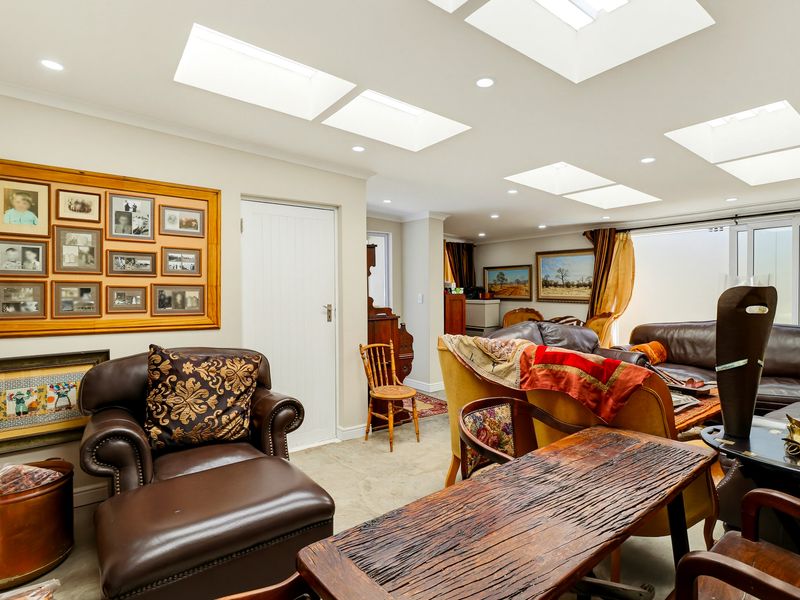 Spacious living area featuring multiple skylights, recessed downlighting, and neutral tiled flooring, creating a bright and open atmosphere.