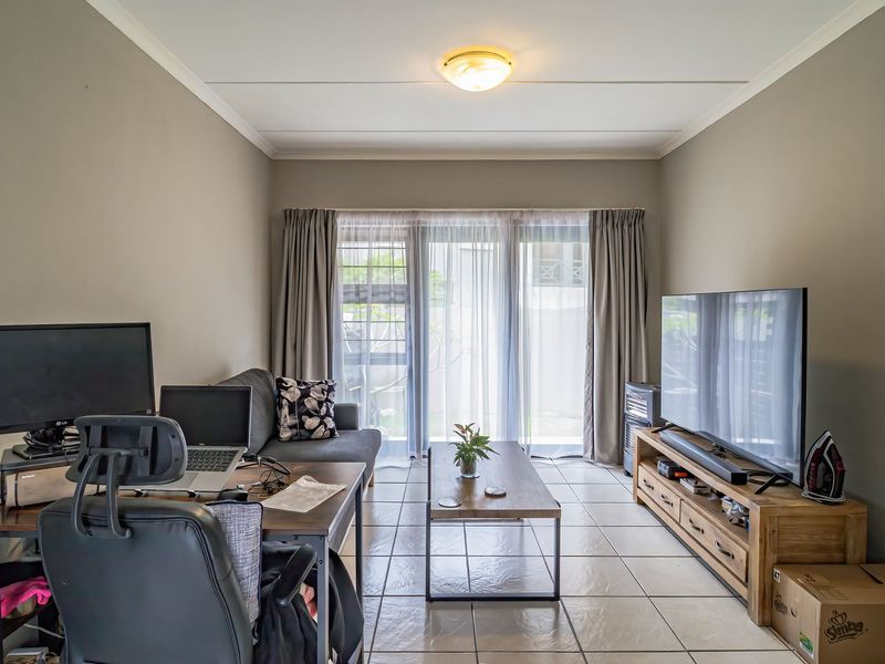 A functional living room featuring tiled flooring and a sliding glass door that provides access to the exterior.