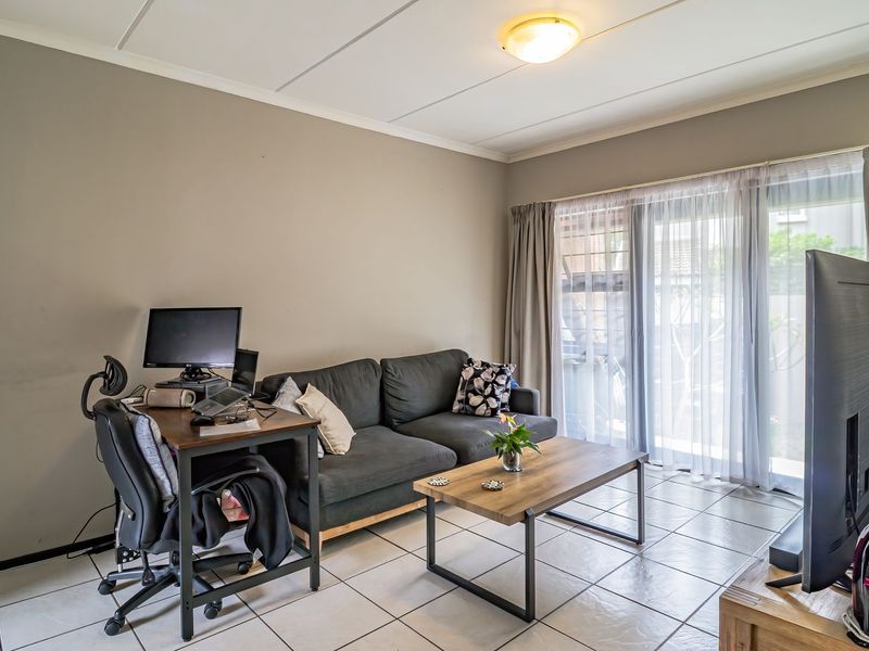 A living room featuring tiled flooring and a sliding glass door providing access to the exterior, offering a functional and well-lit living space.