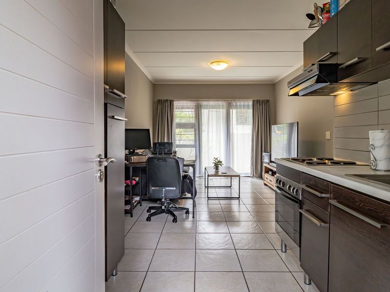 Open-plan living area featuring a modern kitchen with dark cabinetry, tiled flooring, and a sliding glass door leading to the exterior.