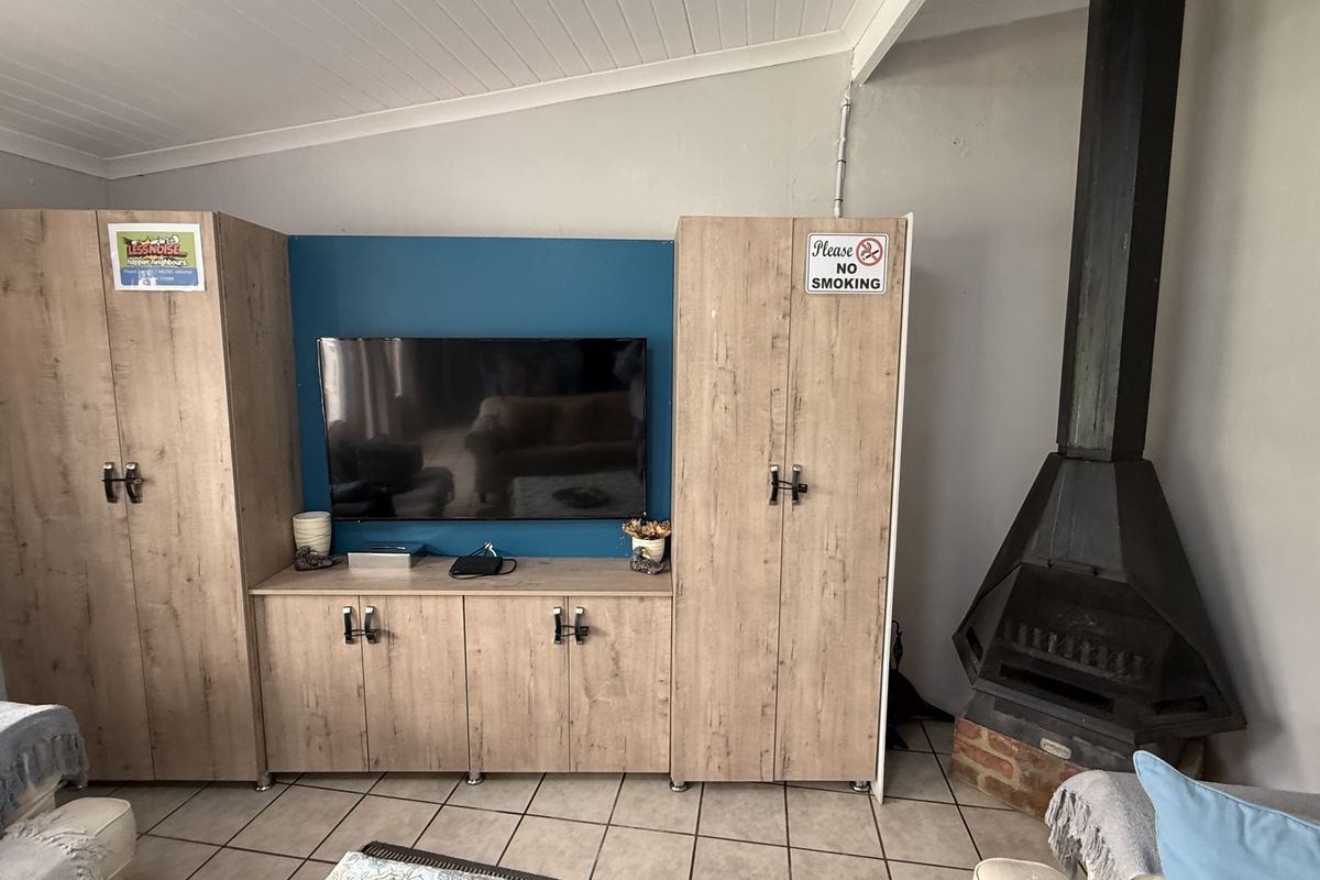 Living room featuring a built-in cabinetry unit, a black metal fireplace, tiled flooring, and a white tongue and groove ceiling.