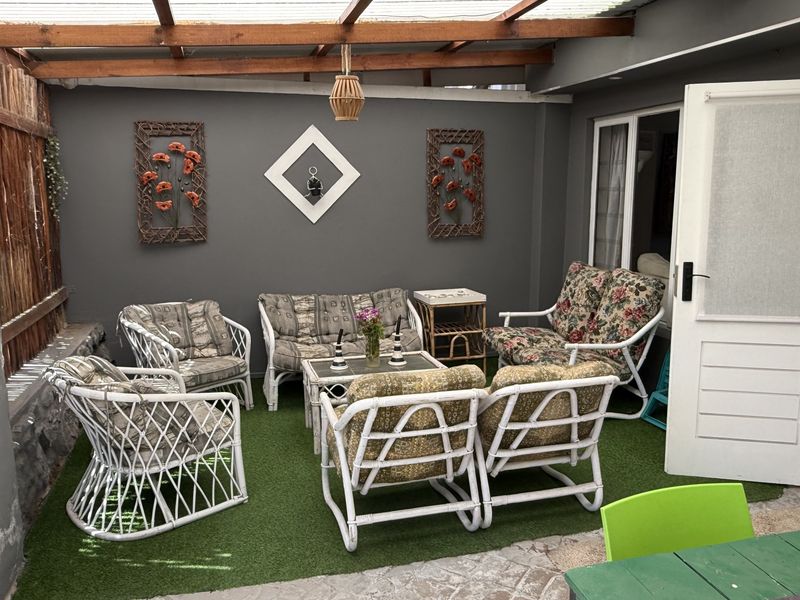 A covered outdoor patio area featuring a timber pergola, artificial turf flooring, and direct access to the interior living space.