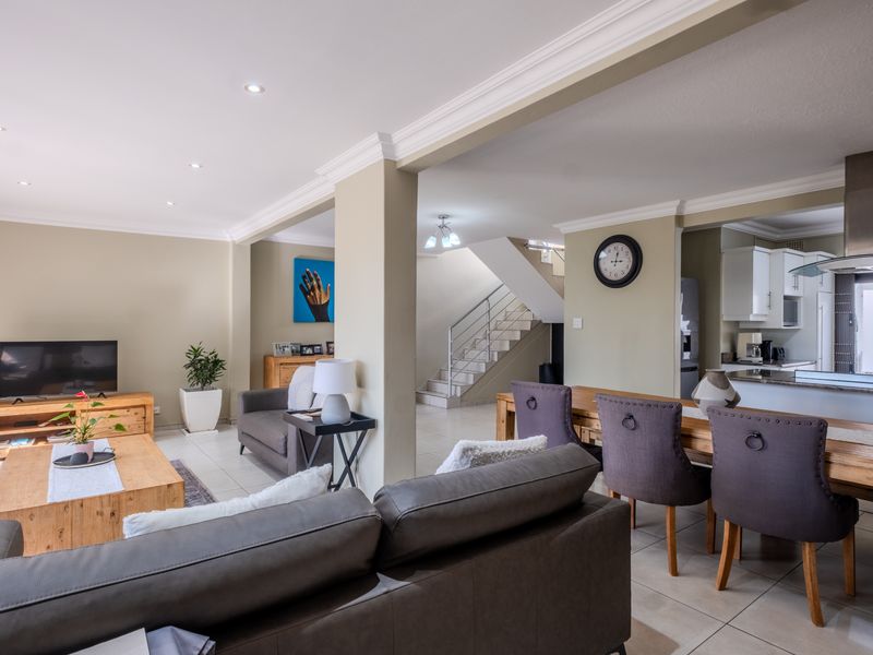 Spacious open-plan living and dining area featuring tiled floors, recessed lighting, crown molding, and a modern kitchen with integrated cabinetry and stainless steel extractor.