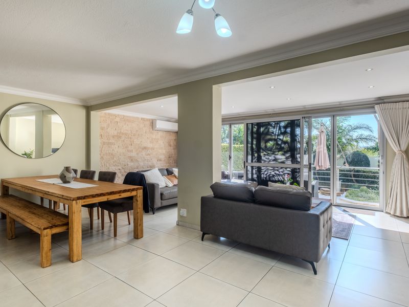 Spacious open-plan living and dining area featuring tiled floors, a stone feature wall, and large sliding glass doors leading to the outdoor patio.