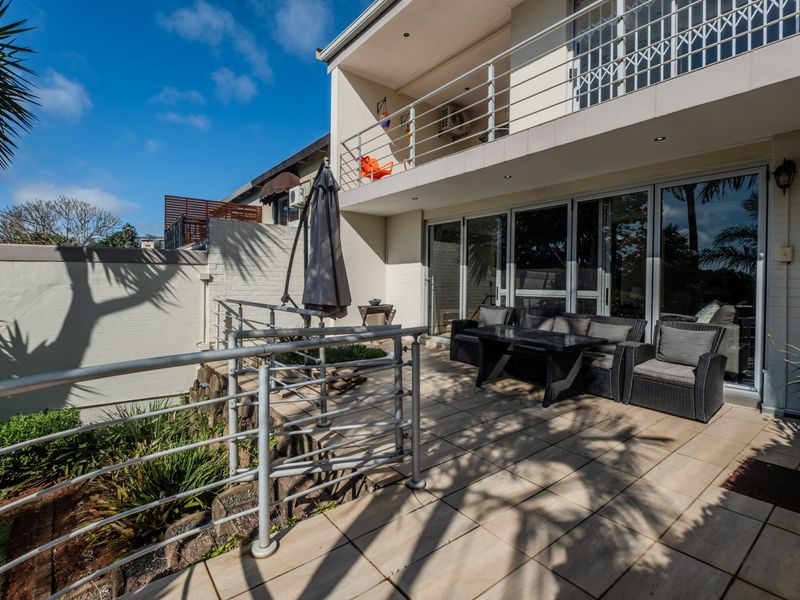 Spacious ground floor patio featuring tiled flooring and metal balustrades, seamlessly connected to the interior living area through large sliding glass doors.