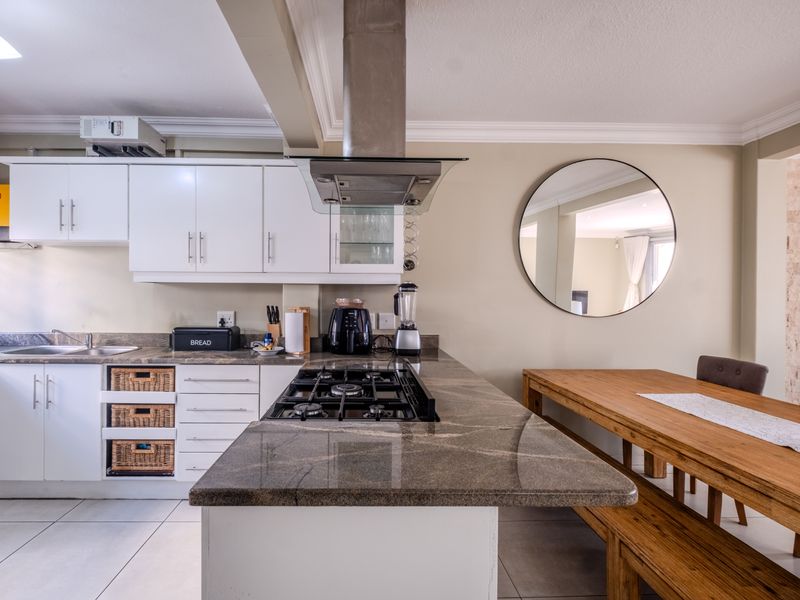 Open-plan kitchen featuring granite countertops, a gas hob with stainless steel extractor, and ample built-in cabinetry, seamlessly flowing into the dining area.
