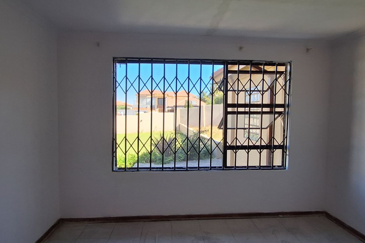 An empty bedroom featuring tiled flooring and a window fitted with a security gate, offering a blank canvas for renovation.