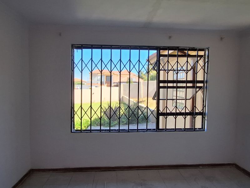 An empty bedroom featuring tiled flooring and a window fitted with a security gate, offering a blank canvas for renovation.