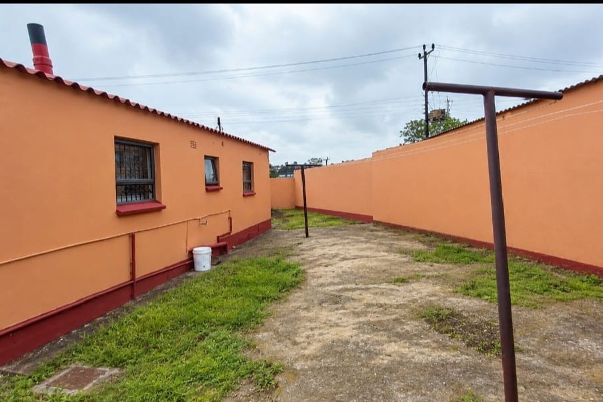 Rear exterior area featuring a concrete paved yard enclosed by a perimeter wall, with access to the side of the house.
