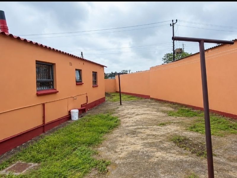 Rear exterior area featuring a concrete paved yard enclosed by a perimeter wall, with access to the side of the house.
