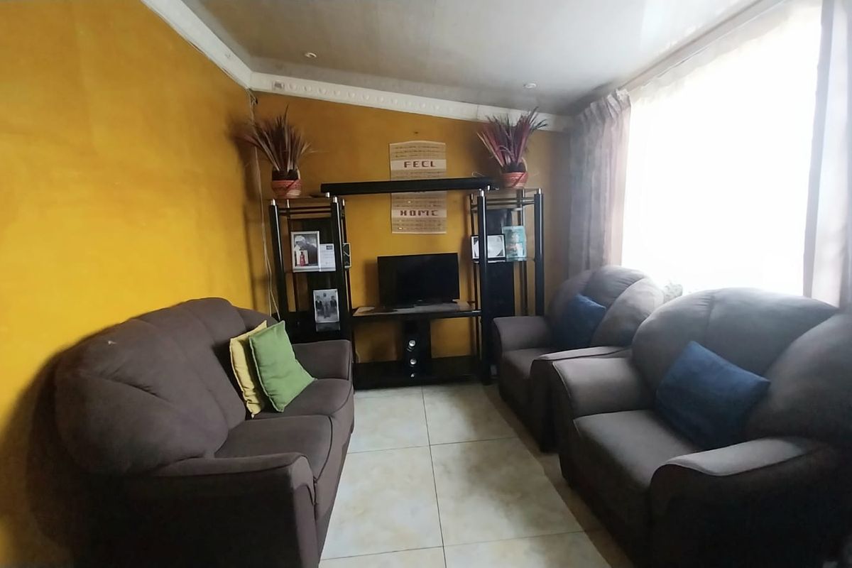 A living room featuring tiled flooring and decorative ceiling cornicing, currently finished with bold yellow wall paint.