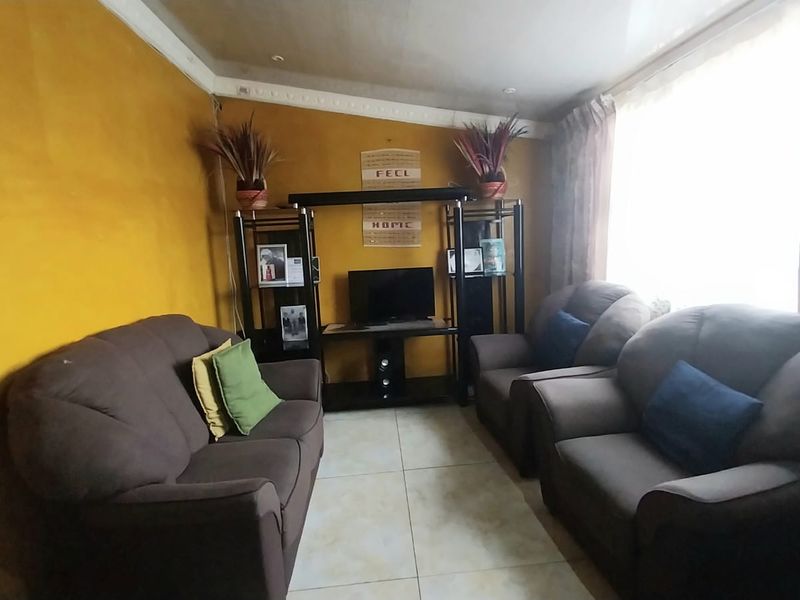 A living room featuring tiled flooring and decorative ceiling cornicing, currently finished with bold yellow wall paint.