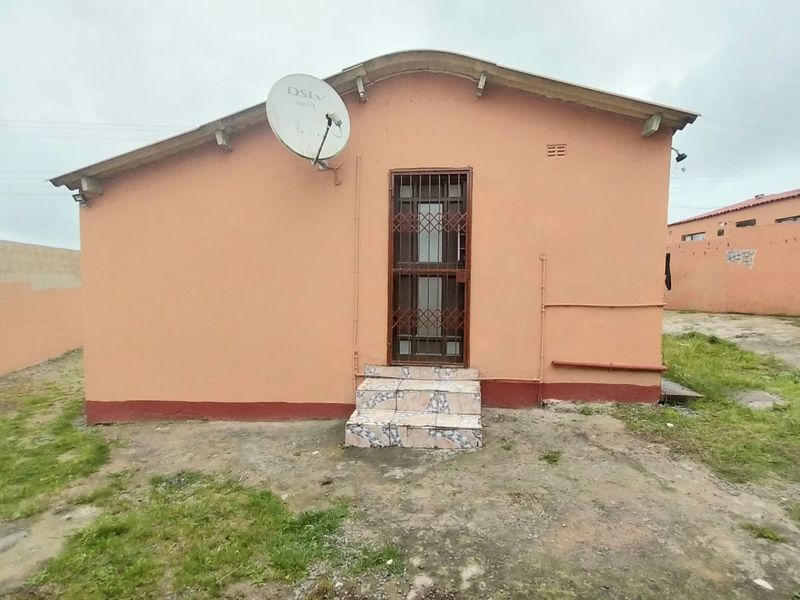 Rear exterior view of the house featuring a security gate, tiled entrance steps, and a satellite dish mounted on the wall.