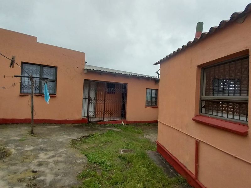 Rear exterior view of the property featuring a concrete courtyard area, security gates, and security bars on the windows.
