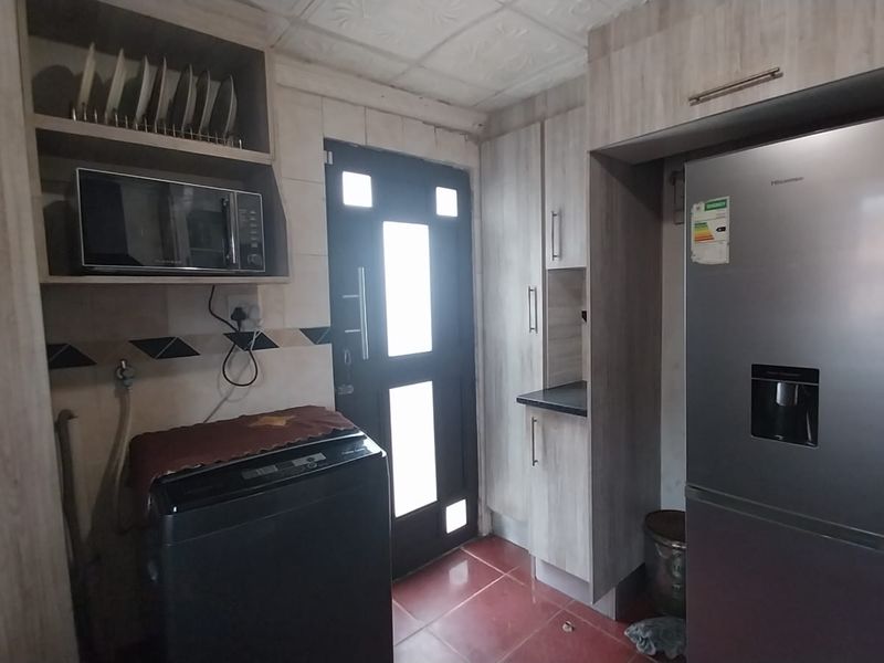 A functional scullery area featuring built-in cabinetry, tiled flooring, and direct access to the exterior.
