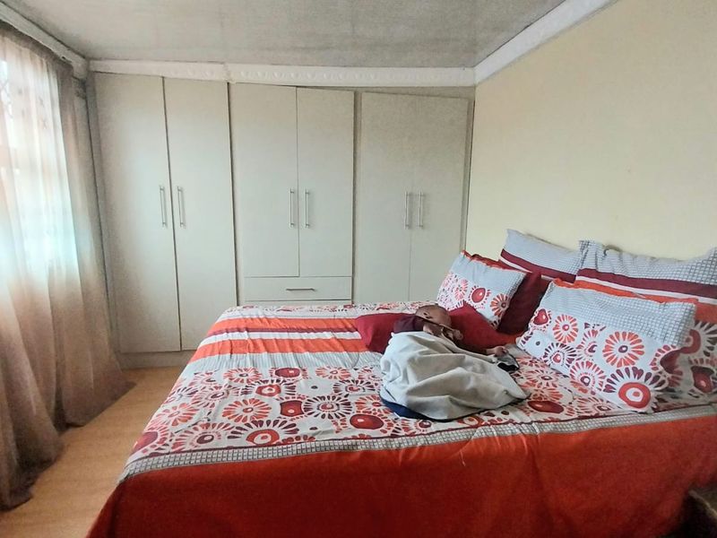 A bedroom featuring built-in cupboards, laminate flooring, and decorative ceiling cornicing.