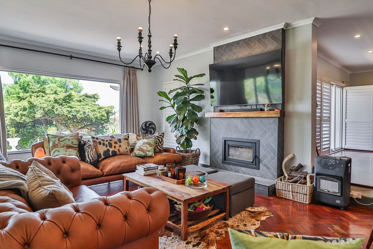 Spacious living room featuring a modern fireplace with herringbone tiling, rich parquet flooring, and large windows providing ample natural light.
