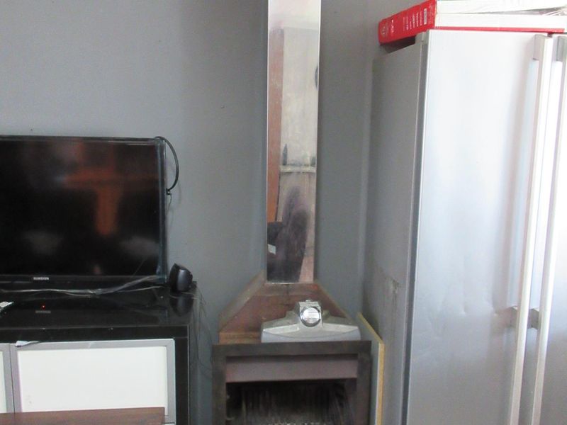 Living area featuring a built-in fireplace with a stainless steel flue and tiled flooring, requiring cosmetic updates to improve the overall aesthetic.