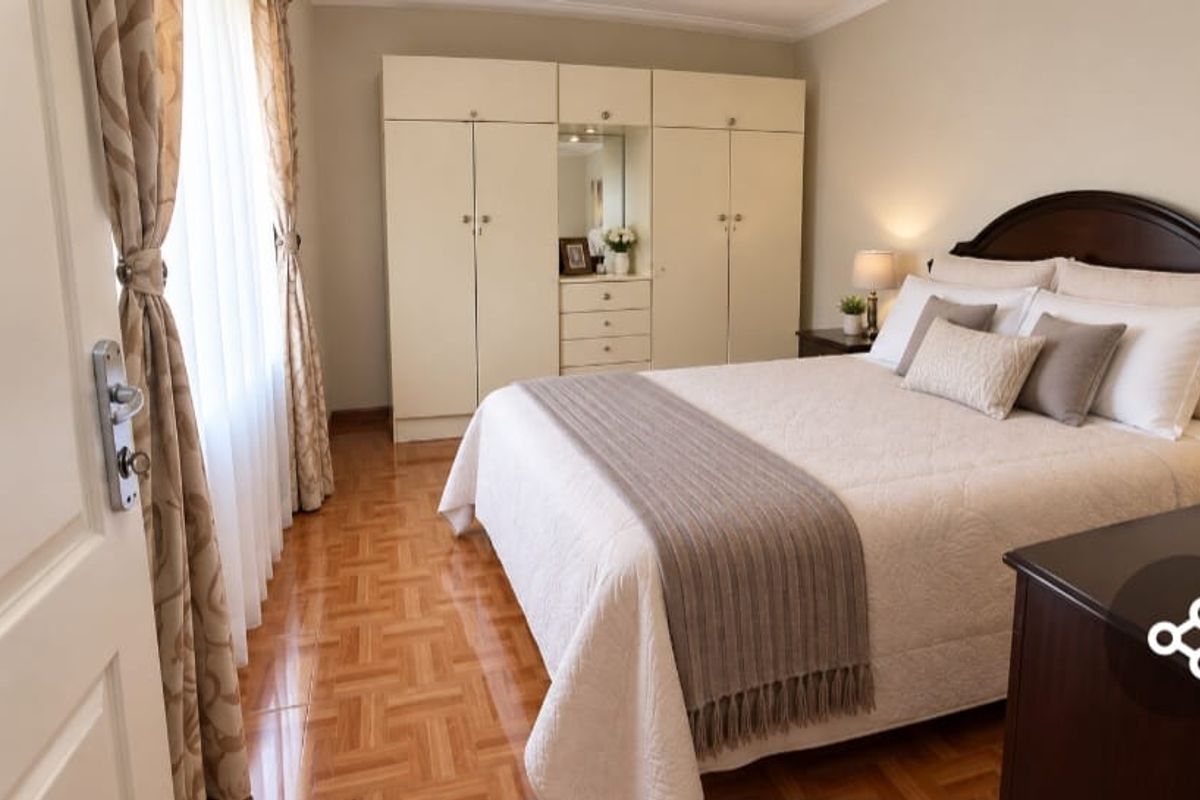 A well-maintained bedroom featuring classic parquet flooring, built-in cupboards, and coved ceiling details, offering a comfortable and functional living space.