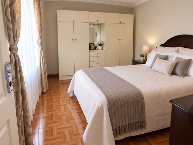 A well-maintained bedroom featuring classic parquet flooring, built-in cupboards, and coved ceiling details, offering a comfortable and functional living space.