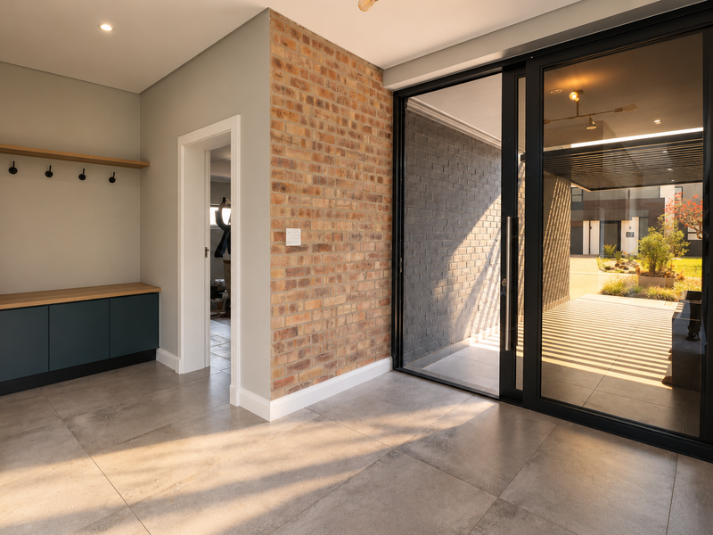 Modern entrance hall featuring an exposed brick wall, built-in storage cabinetry, and large sliding glass doors providing seamless access to the outdoor patio area.