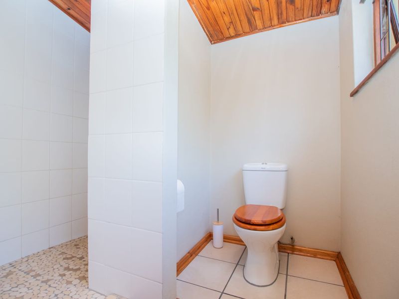 A functional bathroom featuring tiled flooring, a tiled wall partition, and a timber-paneled ceiling.