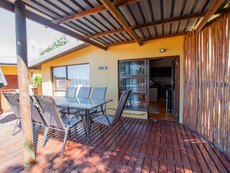 A covered outdoor patio featuring timber decking, a corrugated roof, and a rustic timber screen wall, providing a functional space for outdoor dining.