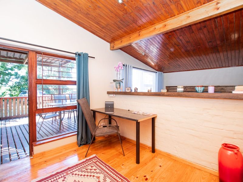A cozy living area featuring a distinctive timber raked ceiling with exposed beams, painted brick walls, and direct access to an outdoor deck.