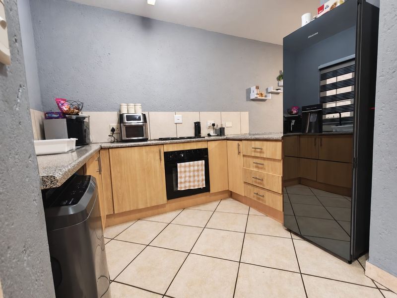 A functional kitchen featuring light wood cabinetry, granite countertops, a tiled backsplash, and tiled flooring, providing a practical workspace.