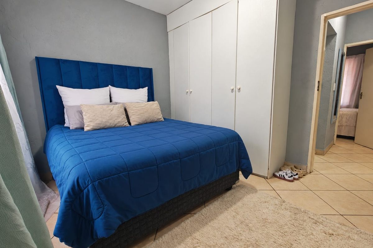 A bedroom featuring built-in cupboards and tiled flooring, offering a functional space with neutral wall tones.