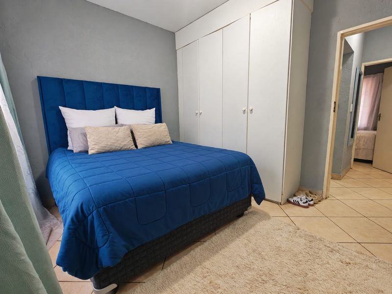A bedroom featuring built-in cupboards and tiled flooring, offering a functional space with neutral wall tones.