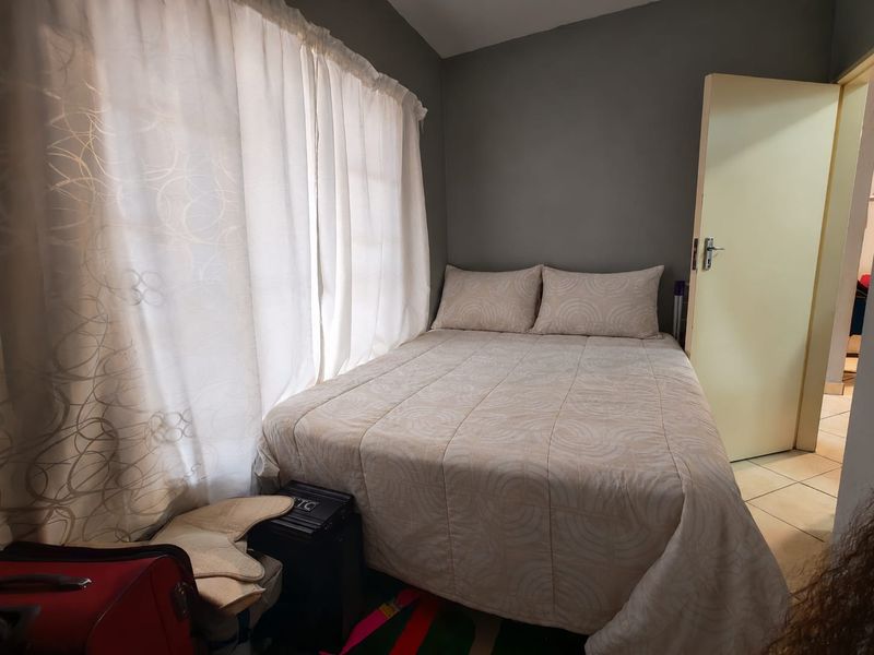A compact bedroom featuring tiled flooring and neutral wall finishes, providing a functional sleeping space.