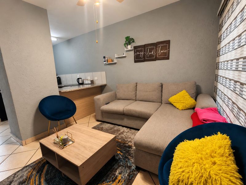 Open plan living area featuring tiled flooring, a breakfast counter, and a ceiling fan, seamlessly connecting to the kitchen space.