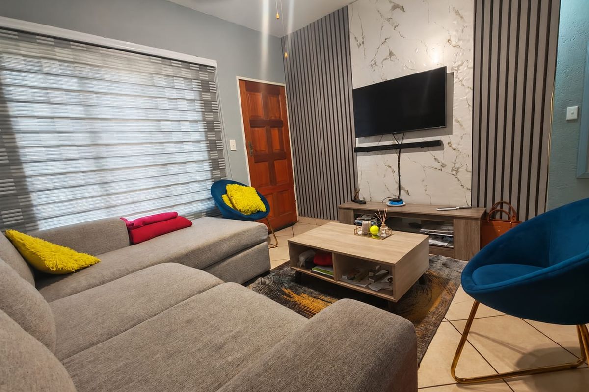 A modern living room featuring a stylish feature wall with slatted paneling and marble-effect cladding, complemented by tiled flooring and neutral decor.
