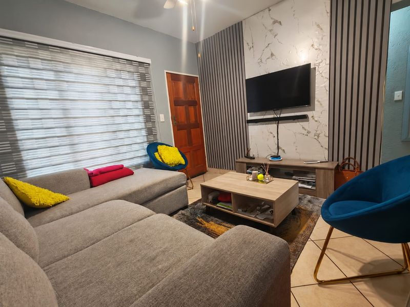 A modern living room featuring a stylish feature wall with slatted paneling and marble-effect cladding, complemented by tiled flooring and neutral decor.