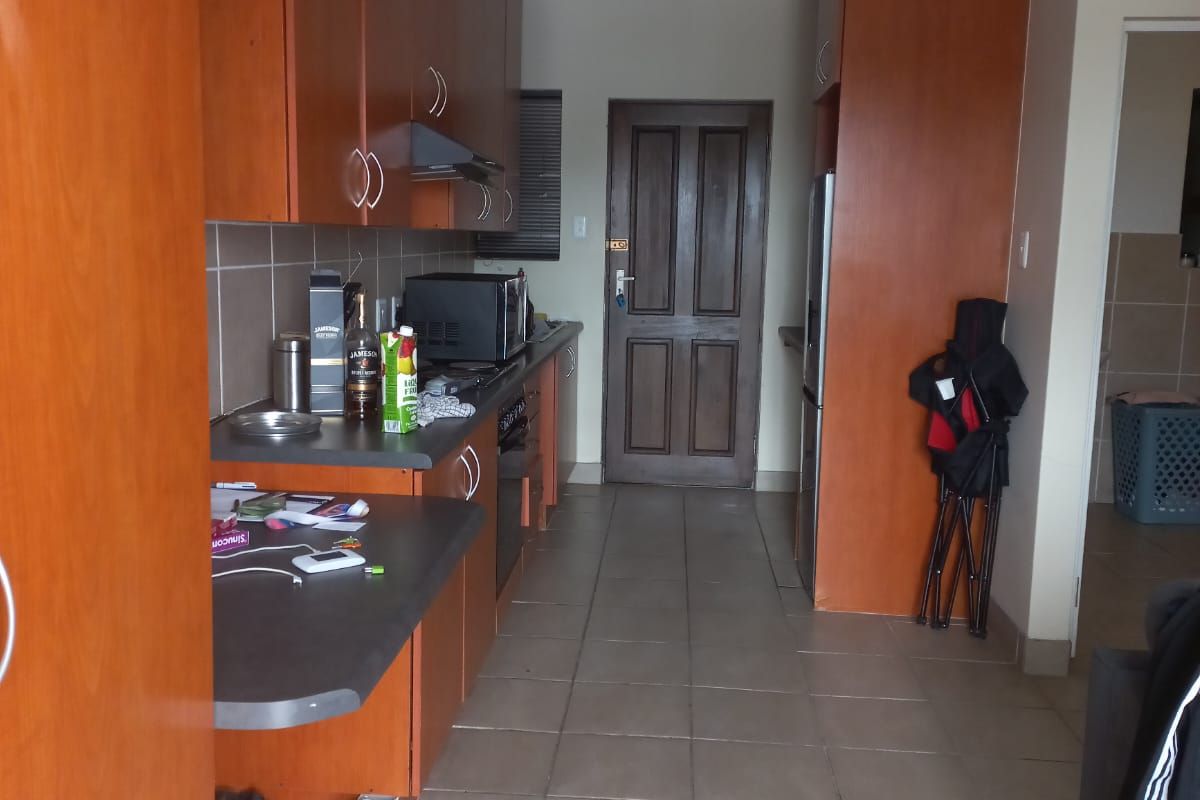 A functional kitchen featuring laminate cabinetry, tiled flooring, and a built-in oven with an extractor fan.