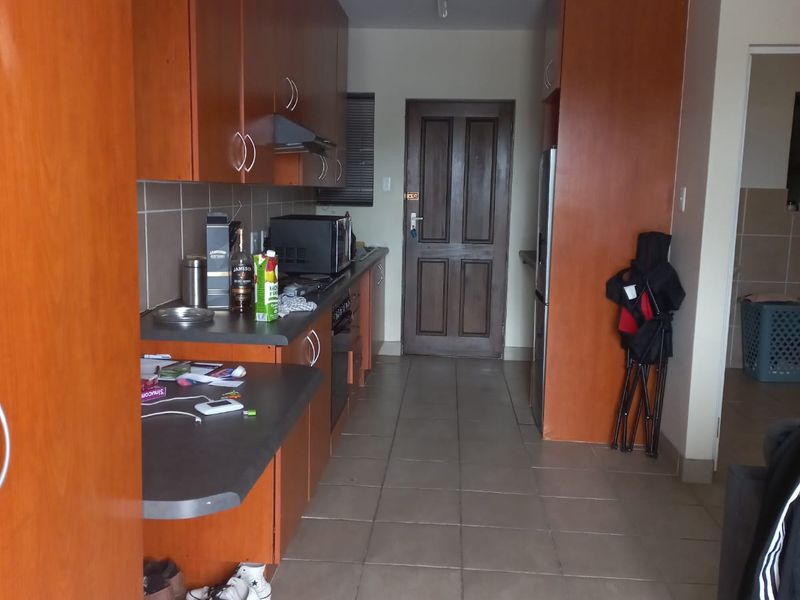 A functional kitchen featuring laminate cabinetry, tiled flooring, and a built-in oven with an extractor fan.
