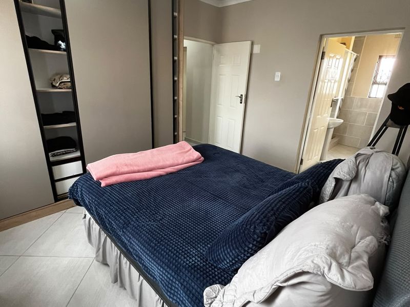 A well-maintained bedroom featuring modern built-in wardrobes, tiled flooring, and direct access to an en-suite bathroom.