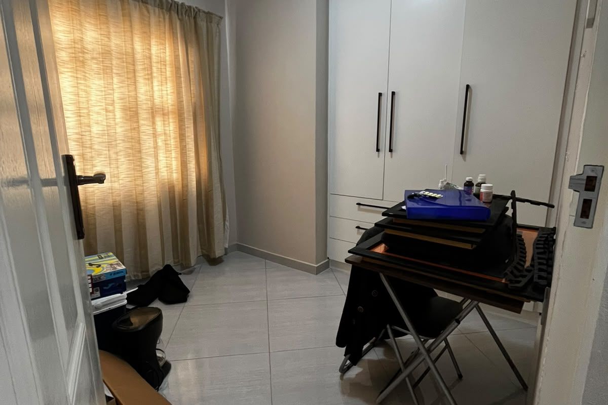A bedroom featuring neutral tiled flooring, coved ceilings, and white built-in cupboards providing ample storage space.