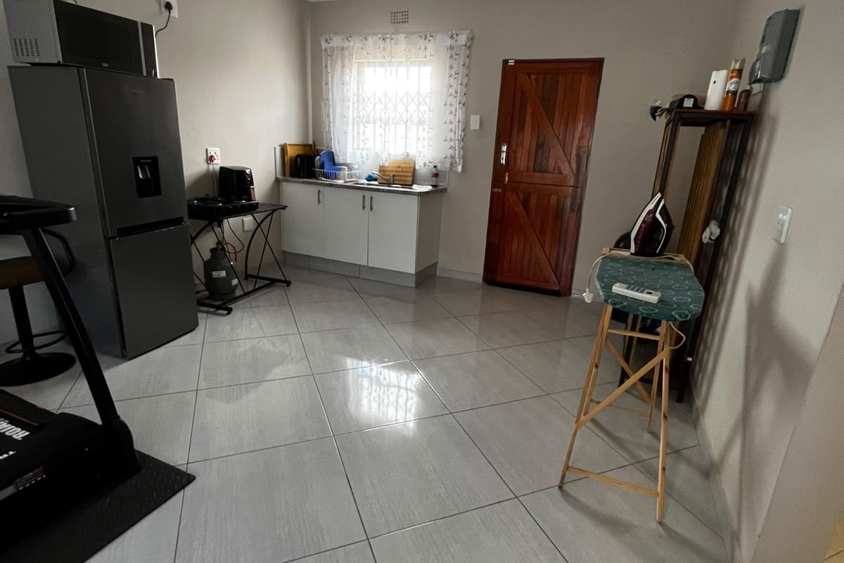 A functional kitchen area featuring tiled flooring, built-in cabinetry, and a secure window with a security gate.