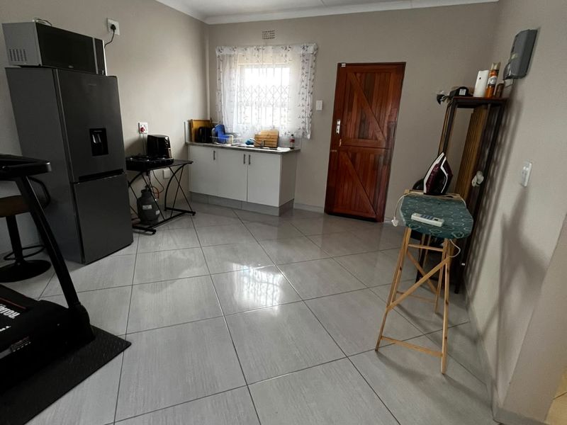 A functional kitchen area featuring tiled flooring, built-in cabinetry, and a secure window with a security gate.