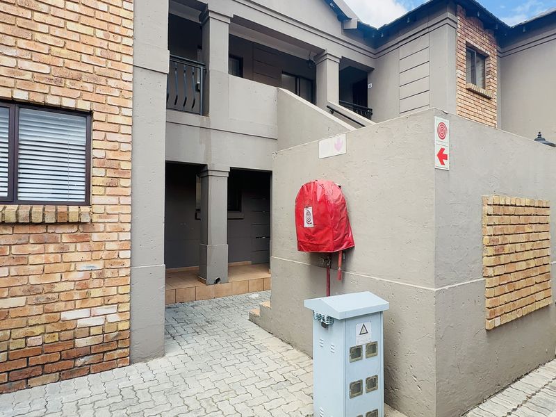 Exterior view of an apartment building featuring brick and rendered facade, paved access area, and integrated fire safety equipment.