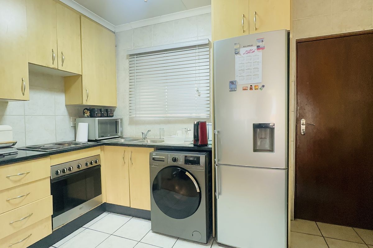 A functional kitchen featuring light wood-toned cabinetry, tiled backsplash, built-in oven and hob, and tiled flooring, offering a practical layout for daily use.