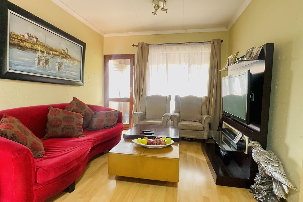 A cozy living room featuring laminate flooring, a sliding glass door providing natural light, and a dedicated media wall area.