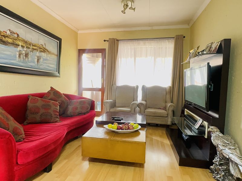 A cozy living room featuring laminate flooring, a sliding glass door providing natural light, and a dedicated media wall area.